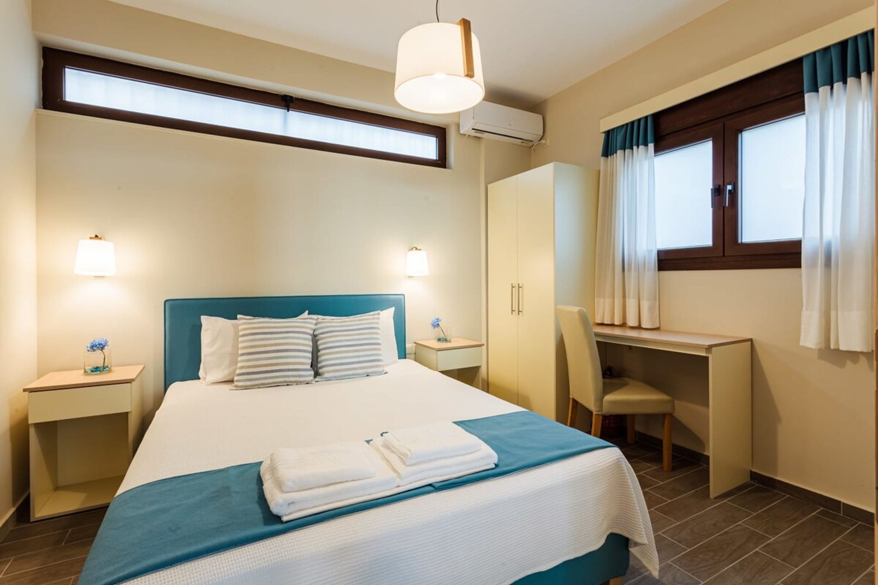A hotel room with a bed, bedside tables, a desk, and a chair.