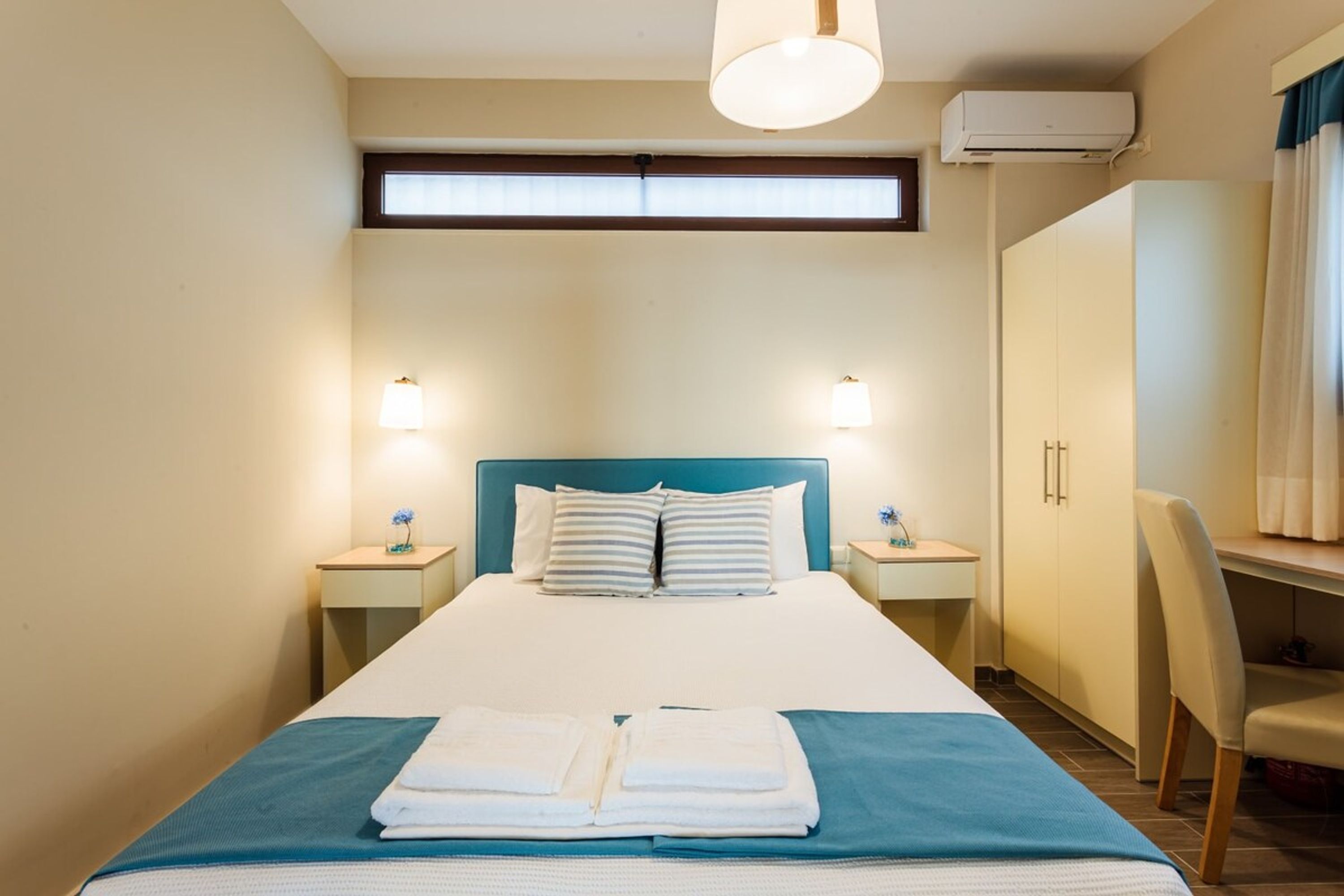 A hotel room with a bed, bedside tables, a desk, and a chair.