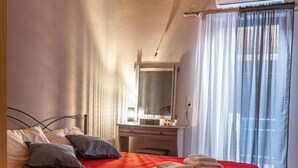 A bedroom with a wooden ceiling, a red bedspread, a bedside table with a mirror, and a window with sheer curtains. - Sunny Summer Retreat - Perfect Location BBQ (Pylos-Nestoras)