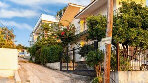 A residential building with a gated entrance, a sign indicating "Konstantina Apartment," and a dirt road leading to the property. - Avia Seaview Getaway - Konstantina s Hidden Haven (West Mani)