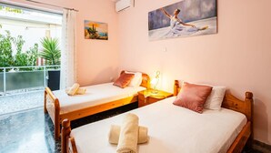 A hotel room with two single beds, a balcony with plants, and a painting on the wall. - Avia Seaview Getaway - Konstantina s Hidden Haven (West Mani)