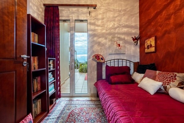 Une chambre à coucher avec un grand lit, une bibliothèque, une porte donnant sur un balcon et un mur décoré de différents objets.