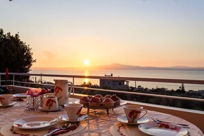 Une table dressée pour le petit-déjeuner, avec vue sur le coucher de soleil sur la mer.