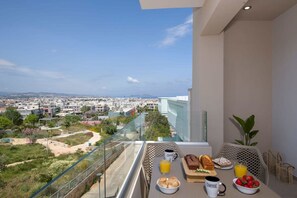 Un balcon avec des éléments pour le petit-déjeuner, une vue sur la ville et une plante.