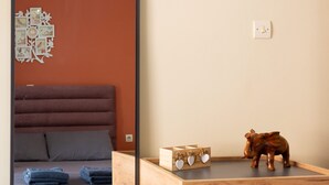 A bedroom with a bed, bedside table, and a mirror reflecting the room. - Kalamata s Handmade Apartment (Kalamata)