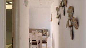 A hallway with a dining area, a bed, and decorative wall art. - Rustic Stone House in the Heart of Folegandros (Folegandros)