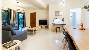 Ένα σύγχρονο σαλόνι με έναν καναπέ, ένα τραπεζάκι σαλονιού και μια σκακιέρα. Υπάρχει επίσης μια τηλεόραση, ένα γραφείο με ένα φωτιστικό και μια τραπεζαρία με καρέκλες.