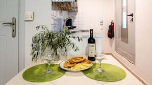 Une cuisine avec une table à manger dressée, où l’on voit de la nourriture et des boissons, une bouteille de vin et une plante en pot.