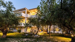 Ένα σύγχρονο διώροφο κτίριο με μια αυλή που διαθέτει έπιπλα για χρήση σε εξωτερικούς χώρους.