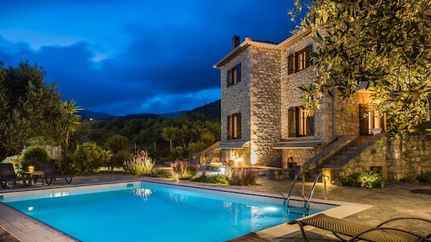 Un edificio in pietra con piscina e area relax all'aperto.