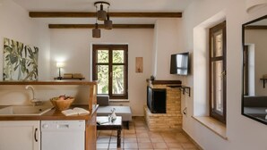 Una cucina compatta con lavastoviglie, un tavolo in legno e un televisore.