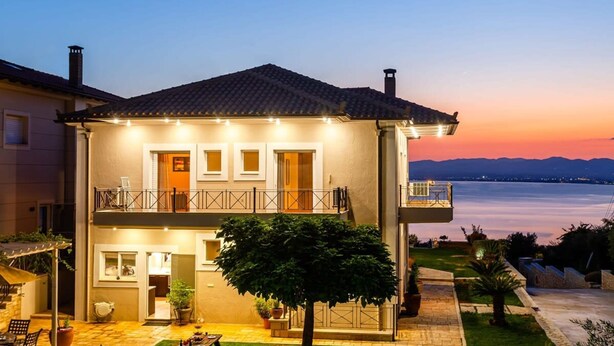 A two-story house with a balcony, a garden, and a view of the water. - Sunset Paradise - Verga s Ultimate Seaview Getaway (Kalamata)
