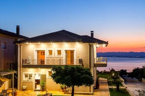 Uma casa de dois andares com varanda, jardim e vista para a água.