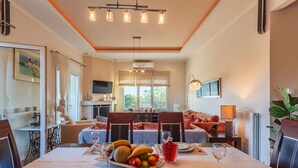 A dining area with a table set for two, a fruit platter, and a red drink. - Navarino Captains Villa - Lux Private Pool Retreat (Trifylia)