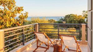 A balcony with two wooden chairs and a wicker table, overlooking a body of water and greenery. - Navarino Captains Villa - Lux Private Pool Retreat (Trifylia)