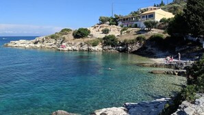 Propiedad costera con vistas despejadas al mar, costa rocosa y un edificio con letrero de restaurante.