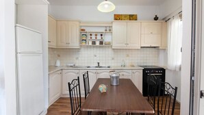 Una cocina con armarios blancos, una mesa de comedor de madera y un lavavajillas negro.