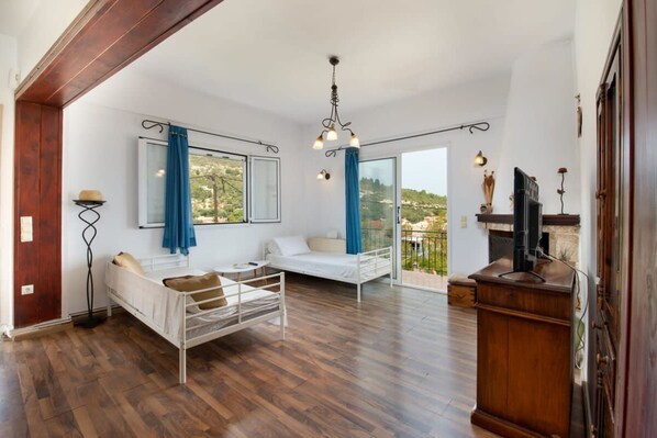 Une chambre spacieuse avec deux lits, un plancher en bois, un balcon avec vue et une cheminée.