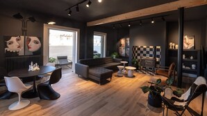 Ein modernes Interieur mit dunkler Farbgestaltung, ausgestattet mit einer Couch, einem Esstisch mit Stühlen und einer karierten Wand.