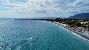 Μια παραθαλάσσια παραλία με καθαρή θέα στη θάλασσα και στα βουνά που διακρίνονται στο βάθος.