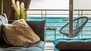 A balcony with a view of the sea, a sofa with a fluffy pillow, and a chair. - Seafront Kalamata Haven - Blue Luxury Suite (Kalamata)