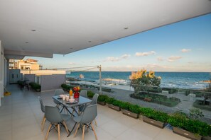 A modern balcony with a view of the sea, a dining area with chairs and a table, and potted plants. - Beachfront Artemida Retreat - Peony Seabreeze Gem (Spata-Artemida)