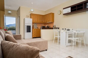 A modern kitchen with wooden cabinets, a white refrigerator, and a dining area with white chairs.