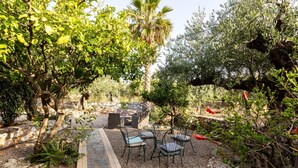 An outdoor seating area with chairs and a table, surrounded by trees and a stone pathway. - Stoupa Oasis - Spitiko Garden Getaway (West Mani)