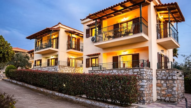 A two-story building with balconies, stone walls, and a well-maintained hedge. - Stoupa Oasis - Spitiko Garden Getaway (West Mani)