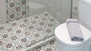 A shower with a glass door, a toilet with a towel, and patterned tiles. - Mear Luxury Suite - The Ultimate Summer Nest (Kantanos-Selino)