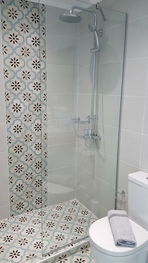 A shower with a glass door, a toilet with a towel, and patterned tiles. - Mear Luxury Suite - The Ultimate Summer Nest (Kantanos-Selino)