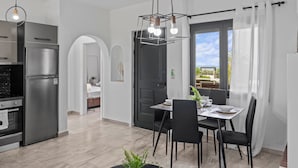 A modern kitchen with a built-in refrigerator, a dining area with a table and chairs, and a view of the outdoors through a large window. - Seaside Charm Near Heraklion Villa Maro II Getaway (Hersonissos)