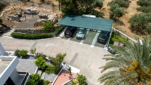 Vue aérienne d’un parking avec trois voitures, une structure abritée et de la végétation environnante.