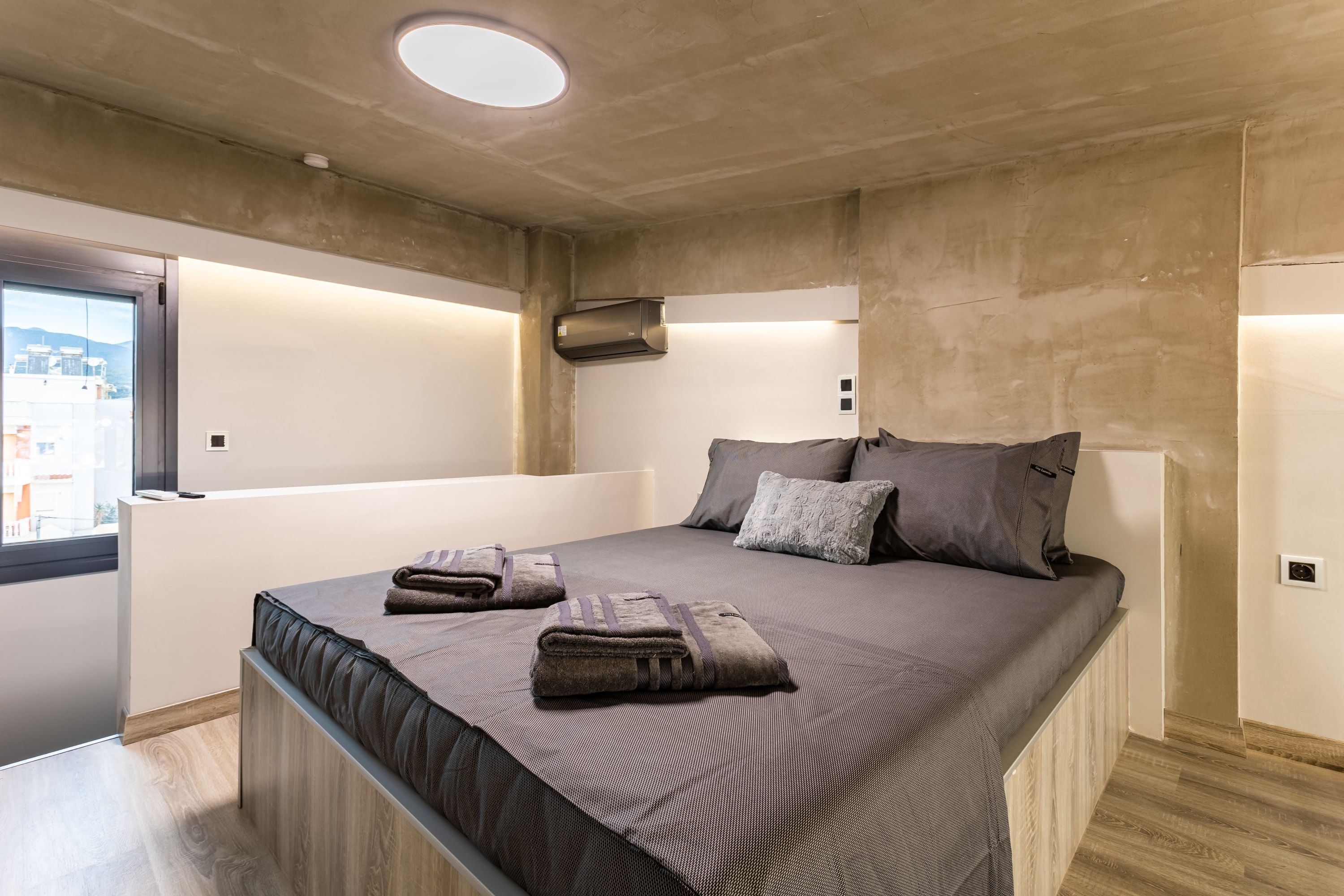 Een moderne slaapkamer met een groot bed, een ingebouwde bank en uitzicht door een raam.