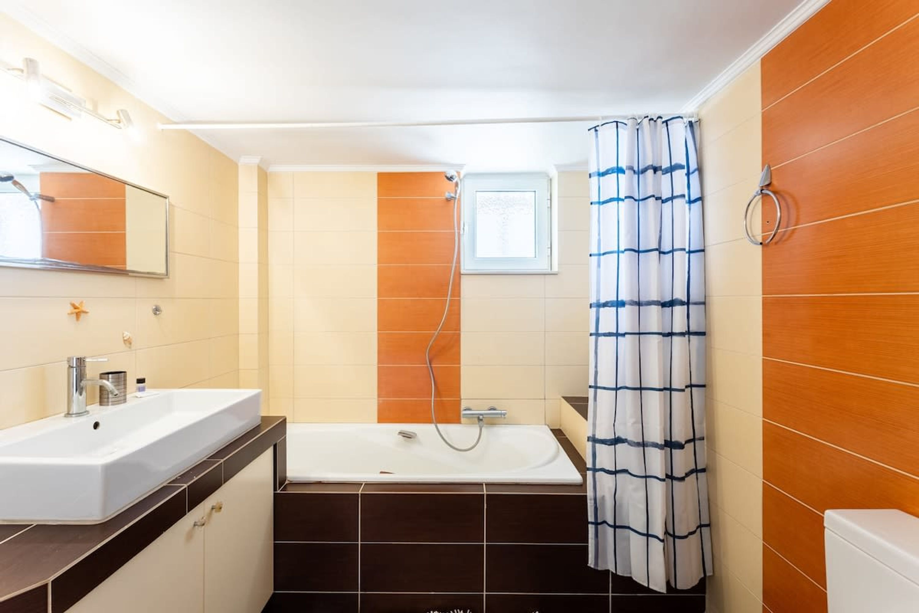 Une salle de bain avec un lavabo blanc, une baignoire et un rideau de douche.