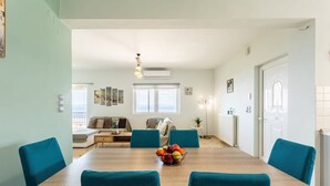 Un comedor con una mesa de madera, sillas color turquesa y un frutero.
