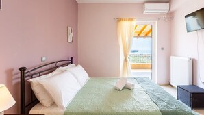 Un dormitorio con cama, mesita de noche, lámpara, televisor y ventana con cortinas.