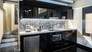 A modern kitchen with a marble countertop, built-in oven, and black cabinetry. - Ventiri Lofts - Luxury Penthouse w Home Cinema (Kalamata)