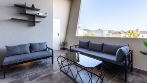 A modern balcony with two grey sofas, a glass coffee table, and minimalist decor. - Ventiri Lofts - Luxury Penthouse w Home Cinema (Kalamata)