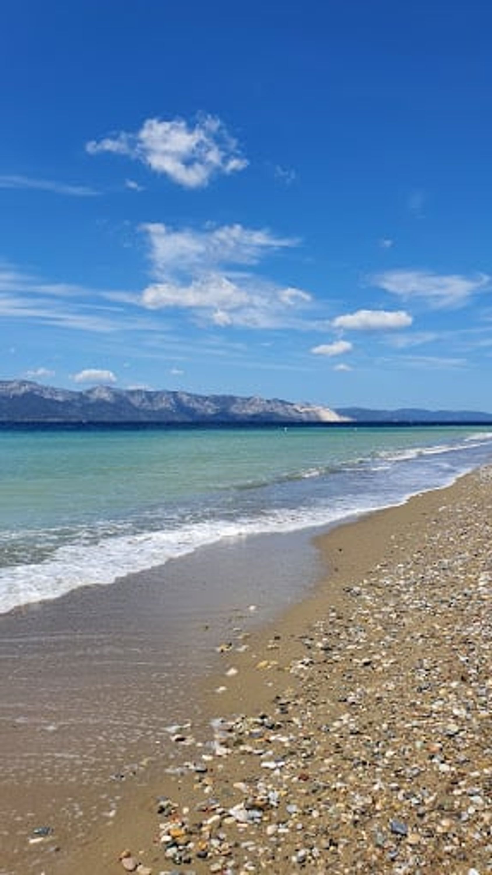 A beach with pebbles and a clear blue sky.