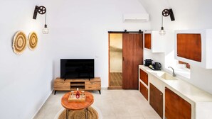 A modern kitchen with a TV, wooden cabinets, and a sliding door. - Santorini Luxury Suite w Rooftop Hottub Seaview (Santorini)