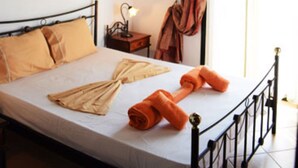 Une chambre à coucher avec un lit, une table de chevet, une lampe, un tableau et une fenêtre avec des rideaux.
