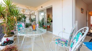 A glass table with chairs, surrounded by potted plants and a lantern. - Bright Comfy Flat Near the Beach the City Center (Kalamata)