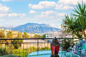 Un balcón con vista a una montaña, una mesa de vidrio y un farol decorativo.