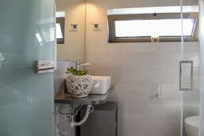A modern bathroom with a white sink, a glass shower enclosure, and a window above the sink. - Coastal Stone Hideaway With Stunning Scenery (West Mani)