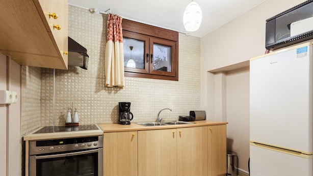 Una cocina compacta con armarios de madera, horno empotrado, cafetera y refrigerador.