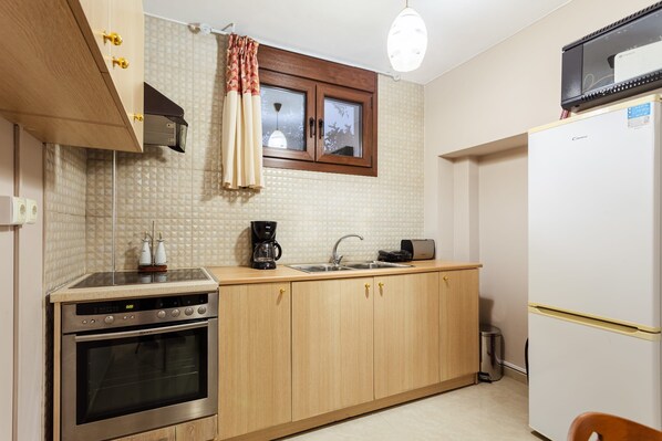 Una cocina compacta con armarios de madera, horno empotrado, cafetera y refrigerador.