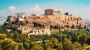 La Acrópolis de Atenas, con el Partenón y otras ruinas antiguas en una colina rodeada de vegetación.