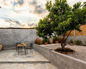 An outdoor patio with stone flooring, a table with chairs, and various potted plants. - Valira Cozy Maisonette - Relaxing Vibes Getaway (Messini)