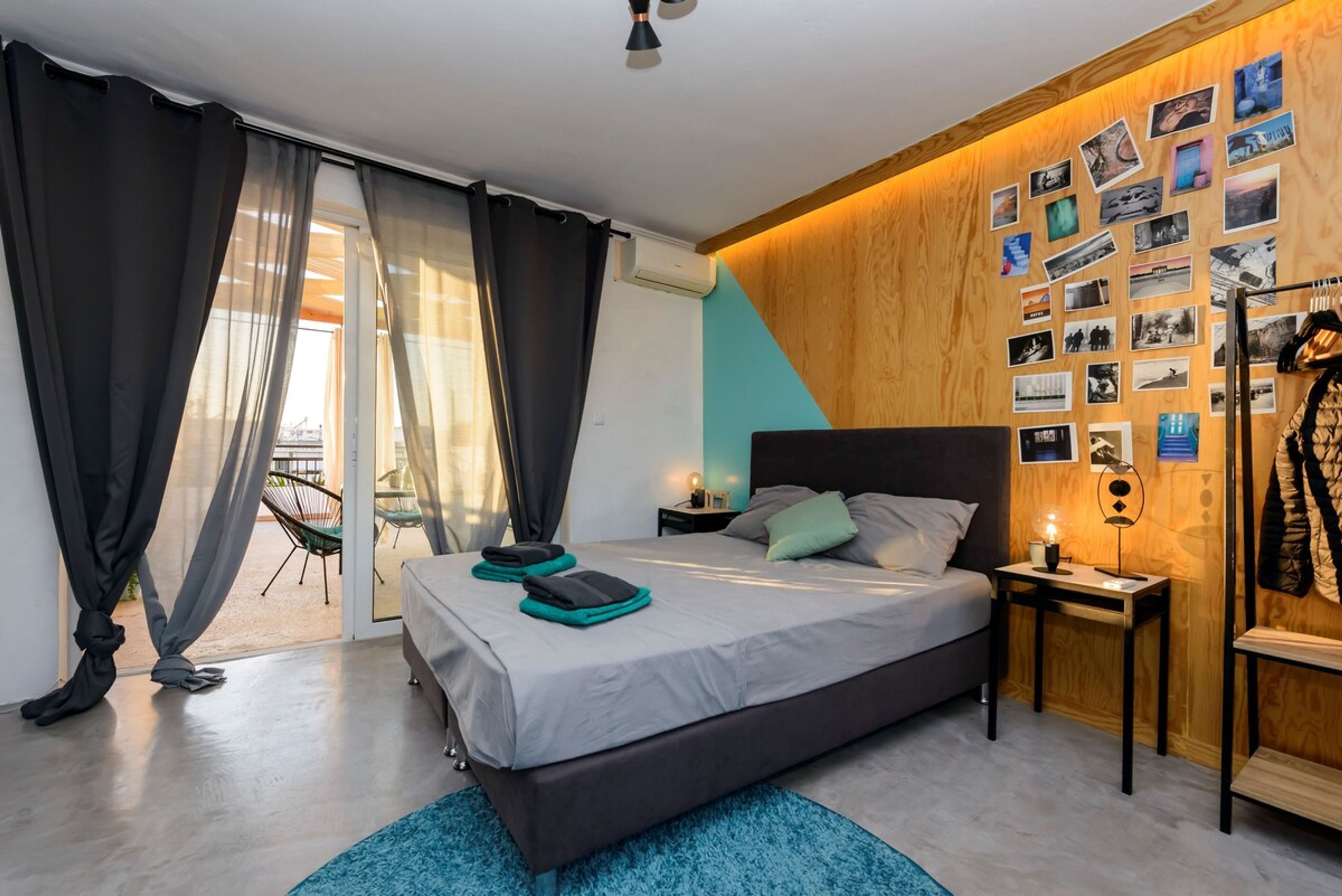 Een moderne slaapkamer met een groot bed, een wand van hout en uitzicht op het groen.